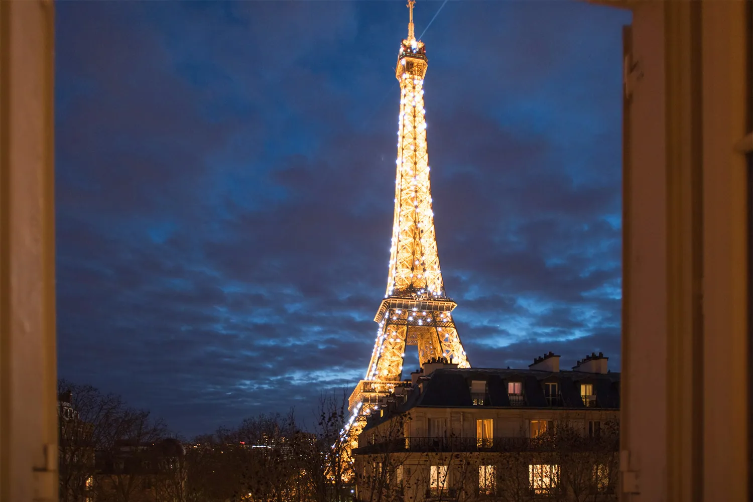 The Eiffel Tower lit at night, seen from the apartment